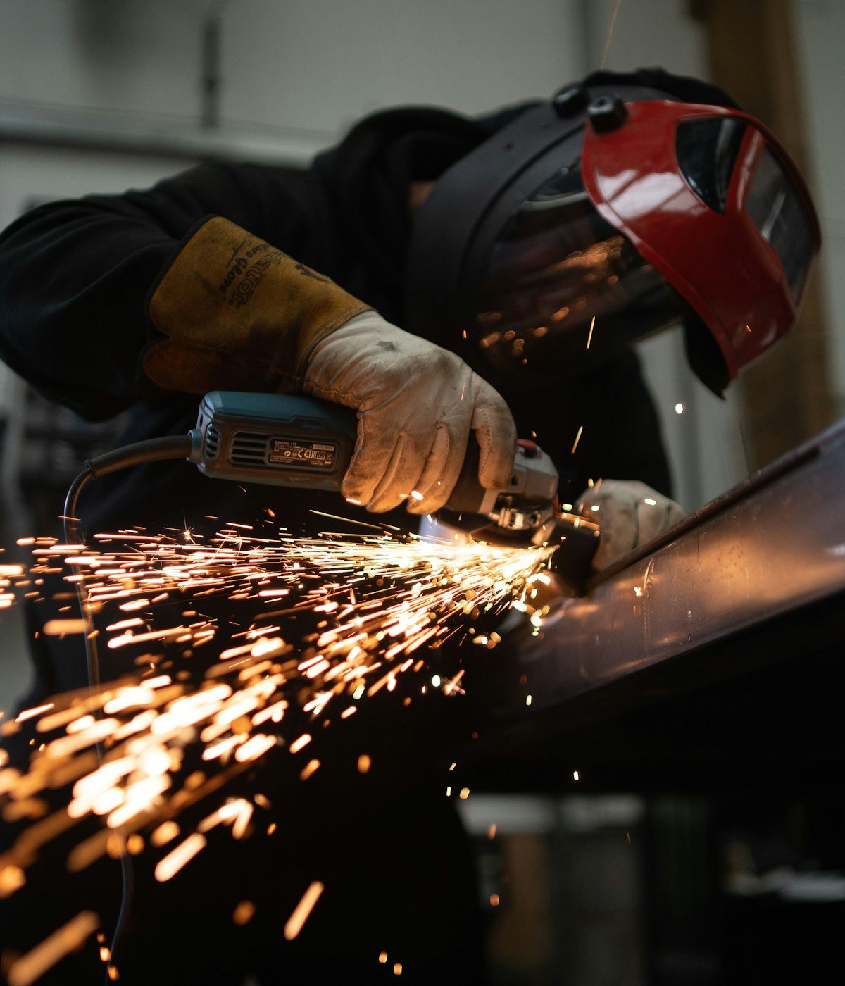 Engineer finishing a metal part with an angle grinder in the workshop